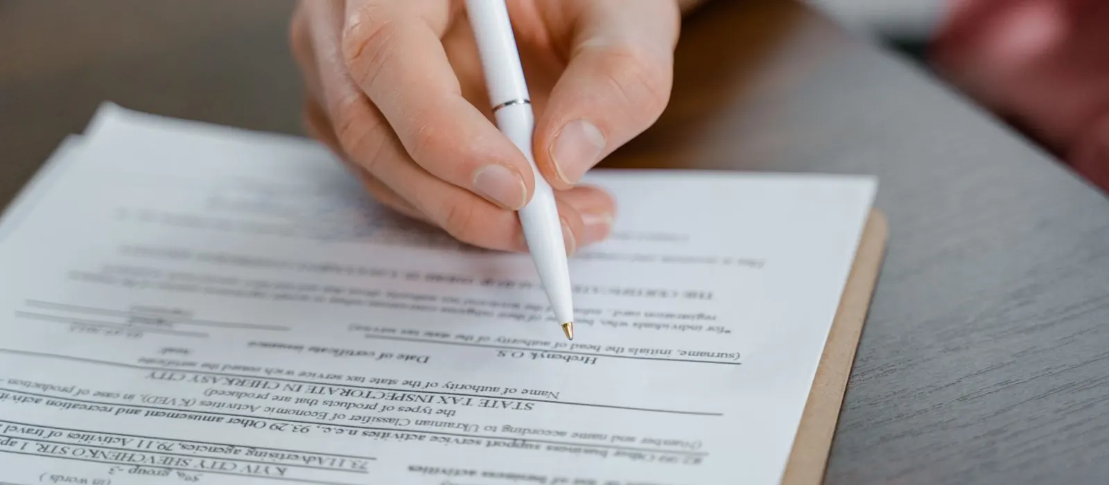 Mano che firma un modulo su una scrivania