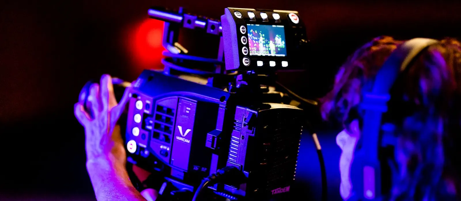 Operatore con cuffie che riprende un palco con una telecamera professionale